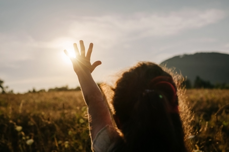 Child reaching toward the sun in a golden field