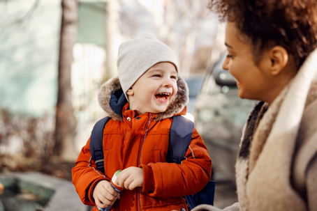 A happy child in a winter coat with a woman.