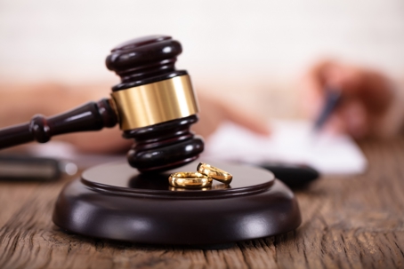 A gavel and two wedding rings on a sound block.